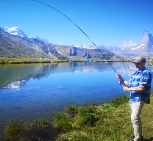 Angler fishing beside a clear alpine lake, photo supplied by you